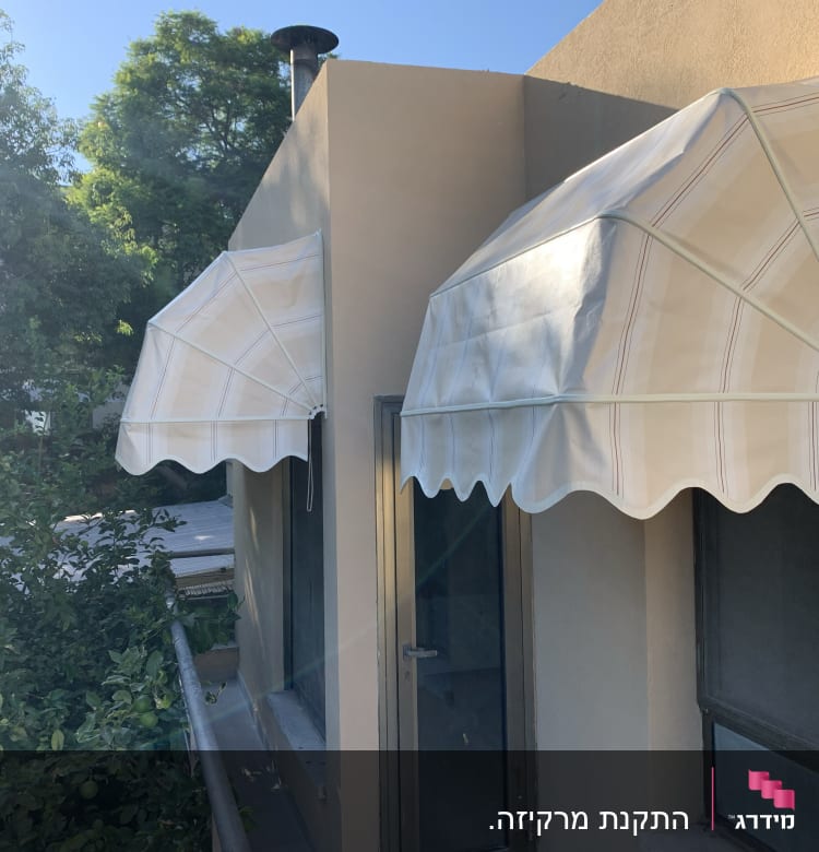 שני סוככים לבנים עם פסים על קיר חיצוני